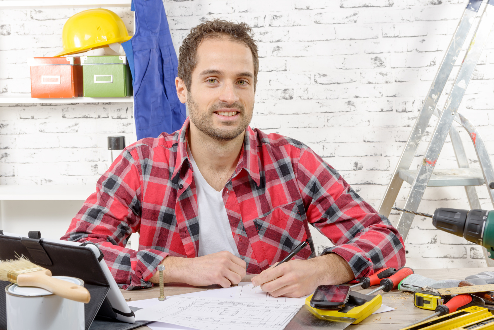 a smiling carpenter sitting at the desk, in his studio