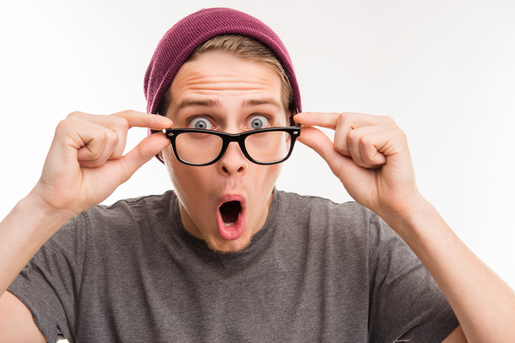 Surprised young hipster in violet cap and glasses with opened mouth