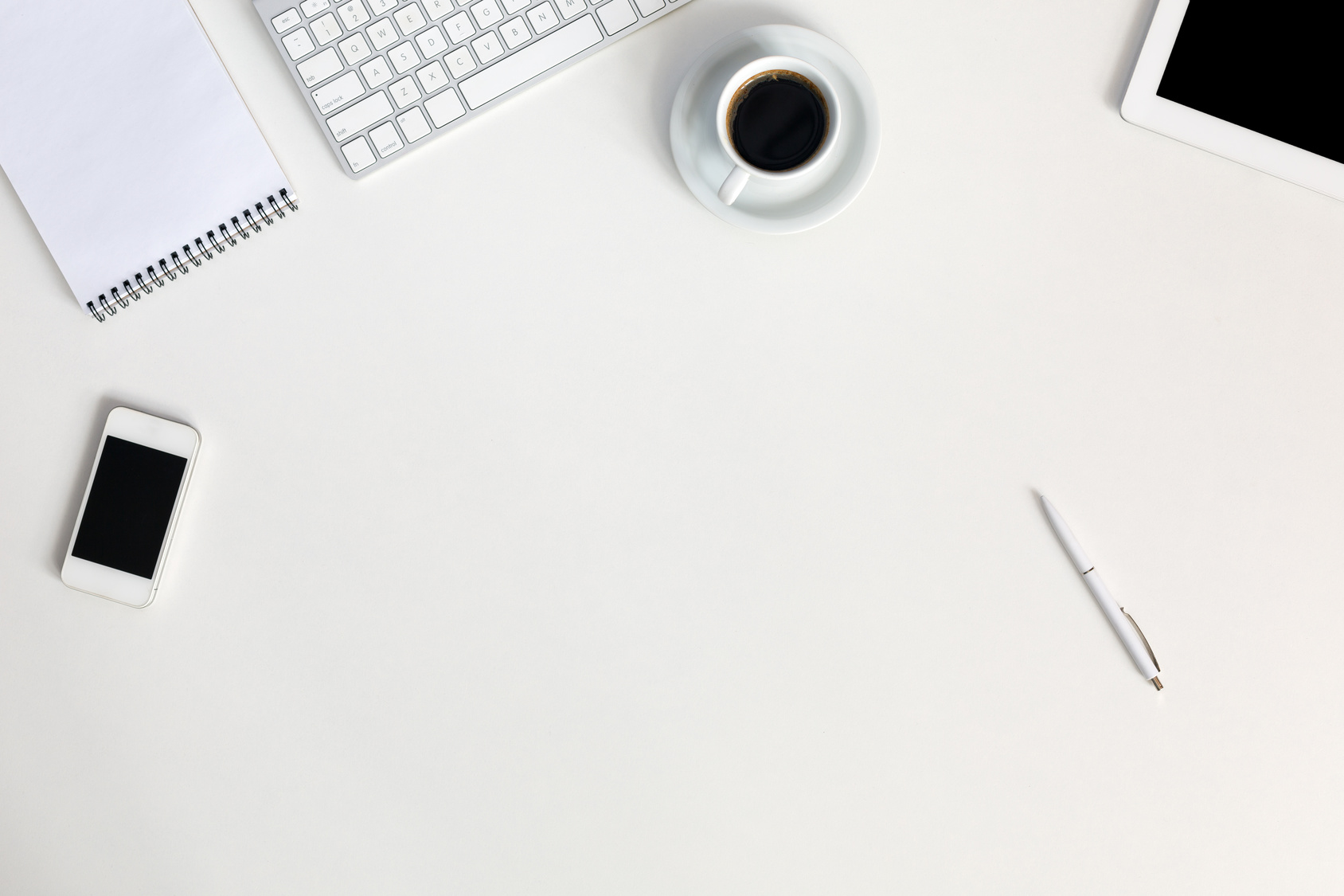 Electronic and Business Items dropped in creative Disorder on white Table Tablet PC Computer Keyboard Telephone Notepad Pen Coffee Cup