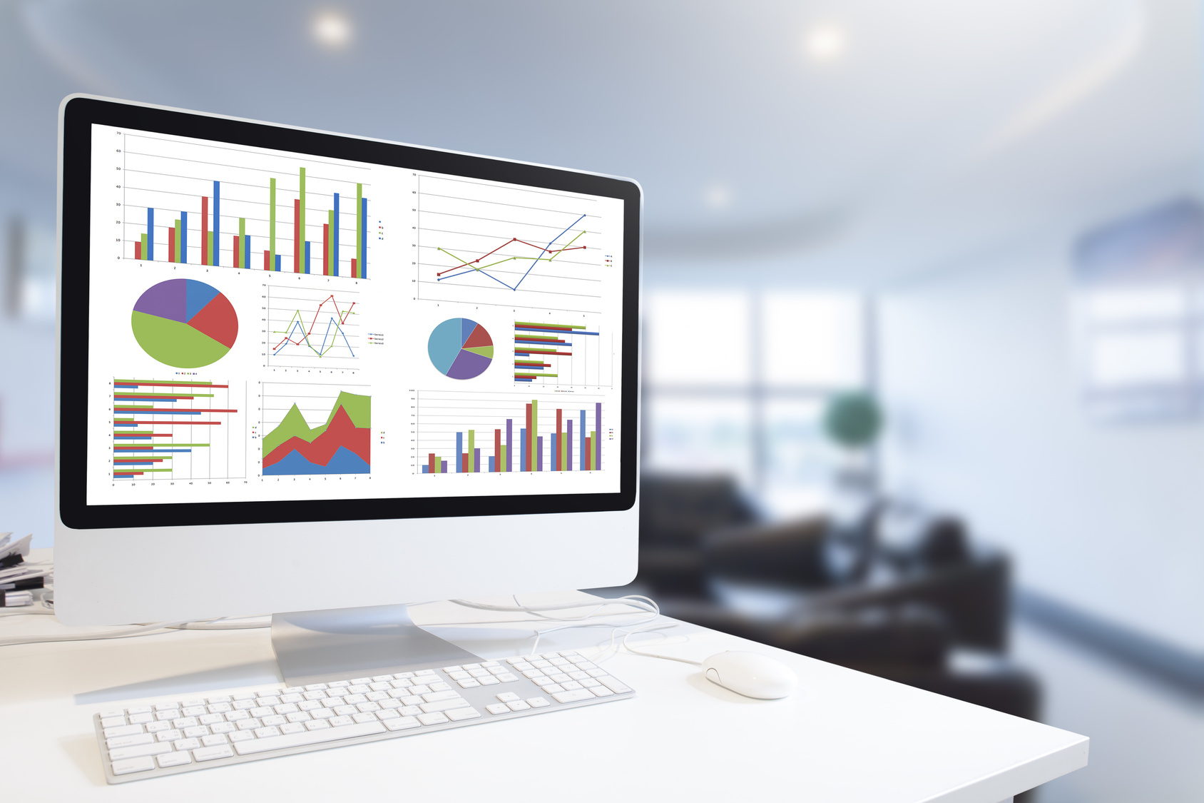 Modern computer with keyboard and mouse on table showing charts and graph against office background in blue tone, Analysis Business, Statistics Concept.