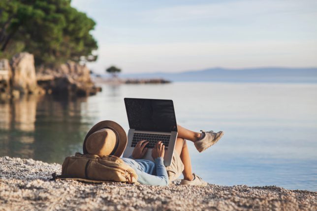 Young,Woman,Using,Laptop,Computer,On,A,Beach.,Girl,Freelancer